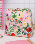 Floral-patterned bag with pink handle on a white surface