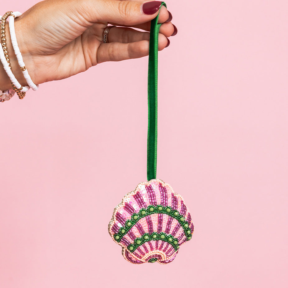 model holding pink and green sequin seashell ornament