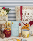 Collection of 'The House at Pooh Corner' themed items including a teddy bear, mug, and tote bag.