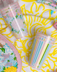 Two colorful cups, one with floral design and the other with striped pattern, on a colorful background.