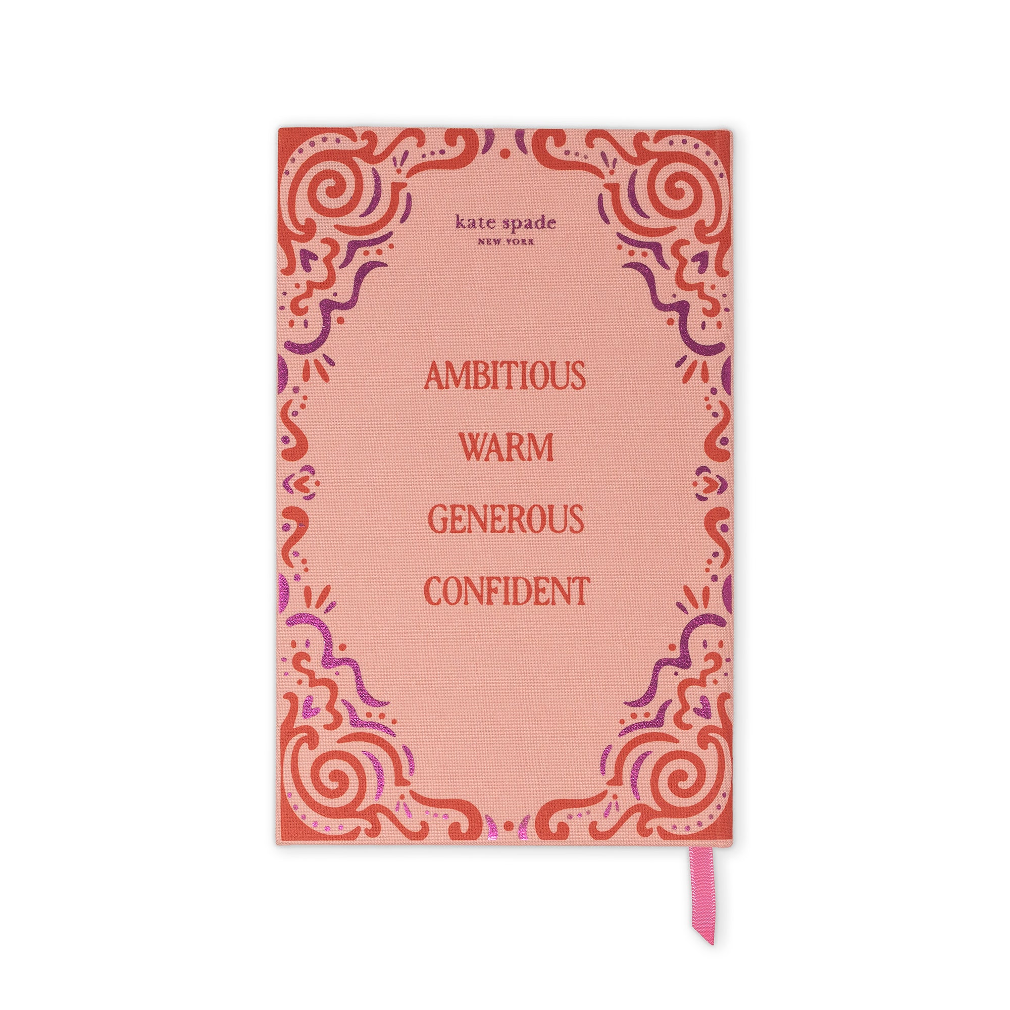 Kate Spade New York notebook with a coral pink cover, featuring a red and purple ornate border design and the words 'AMBITIONOUS WARM GENEROUS CONFIDENT' printed in red. A pink ribbon bookmark is visible at the bottom right.