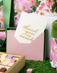 Floral-themed stationery set with a card and mug on a grass-like surface