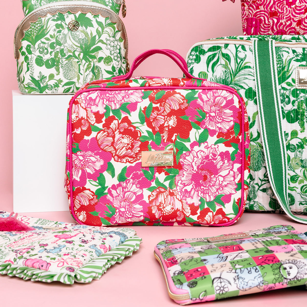 A rectangular cosmetic bag with a vibrant pink, red, and green floral print on a cream background, featuring pink handles and a gold-tone brand plaque. on a pink background surrounded by LP items