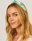 Woman wearing a green floral headband against a plain background