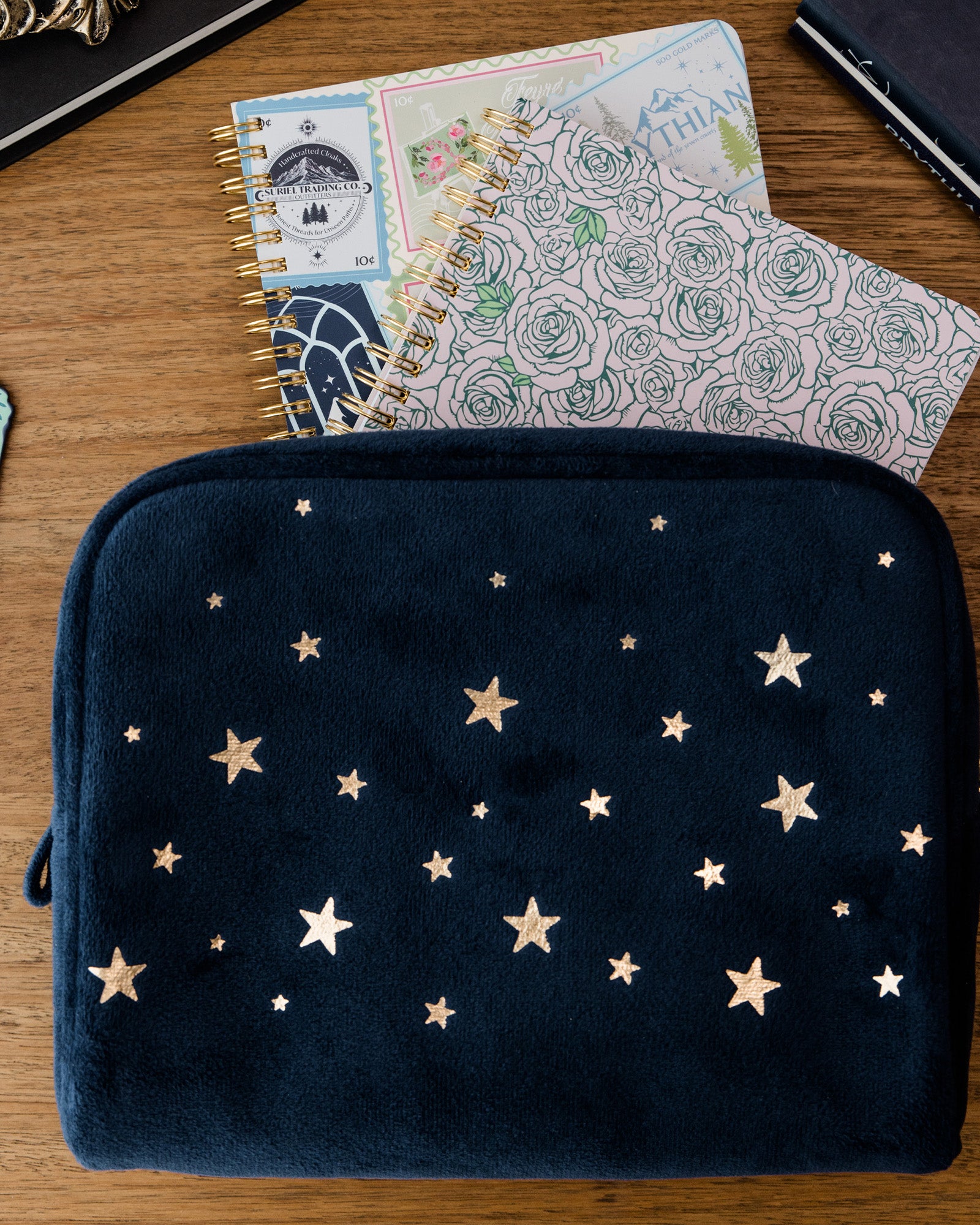 Navy pouch with star pattern on a wooden surface with notebooks and scissors.