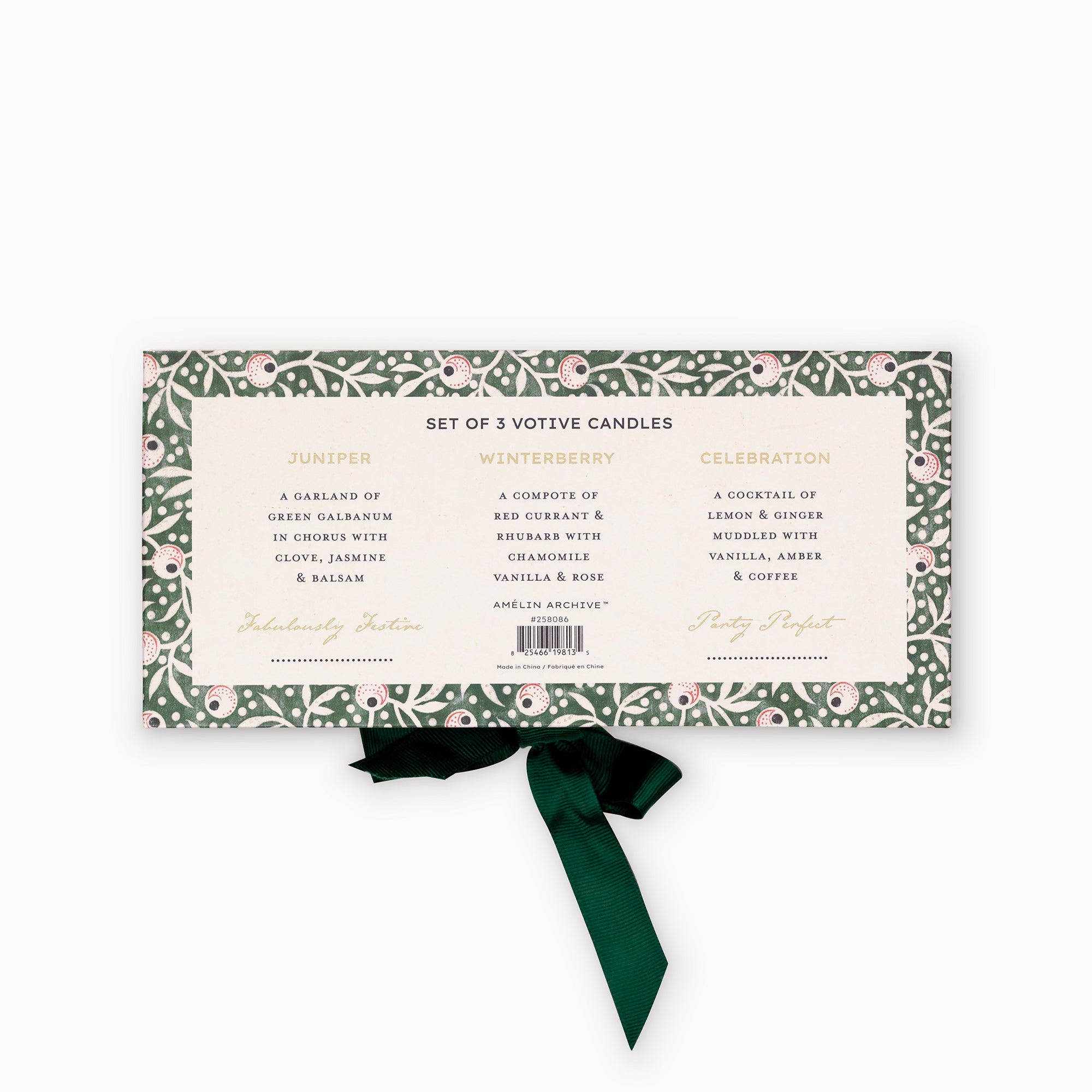A boxed set of three scented votive candles in a rectangular package with a green floral border, cream center label, and a dark green ribbon tied below. The front text reads 'SET OF 3 VOTIVE CANDLES' with scent names Juniper, Winterberry, and Celebration, plus brand text 'Amelie's Archive'.