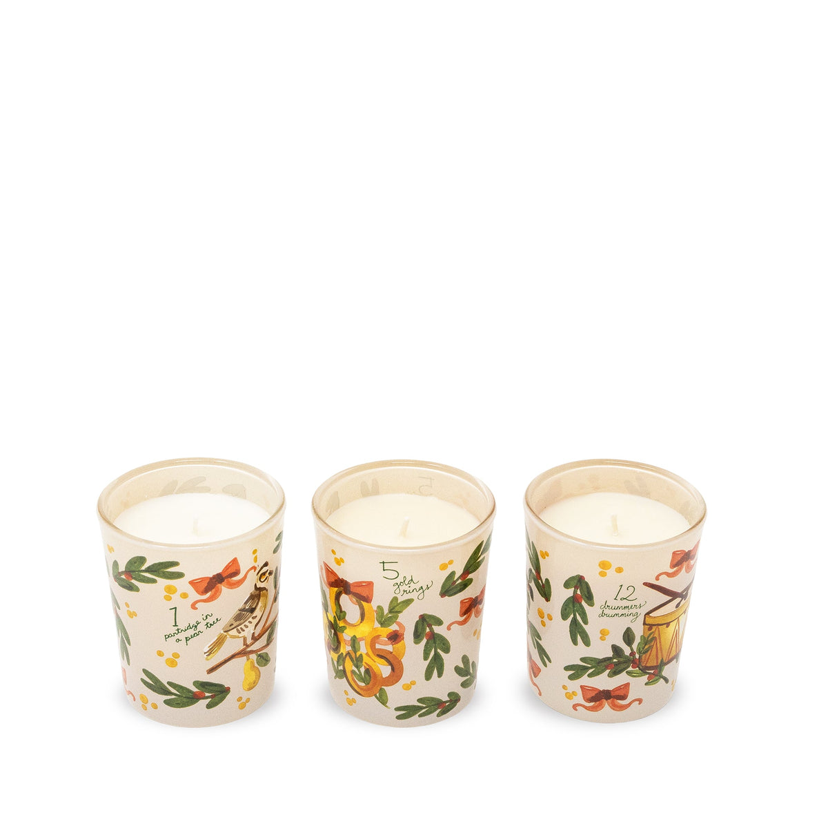 Three small glass jar candles with cream-colored wax and holiday illustrations, arranged in a row on a plain white background.