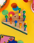 Colorful wooden peg puzzle on a yellow surface with toys around