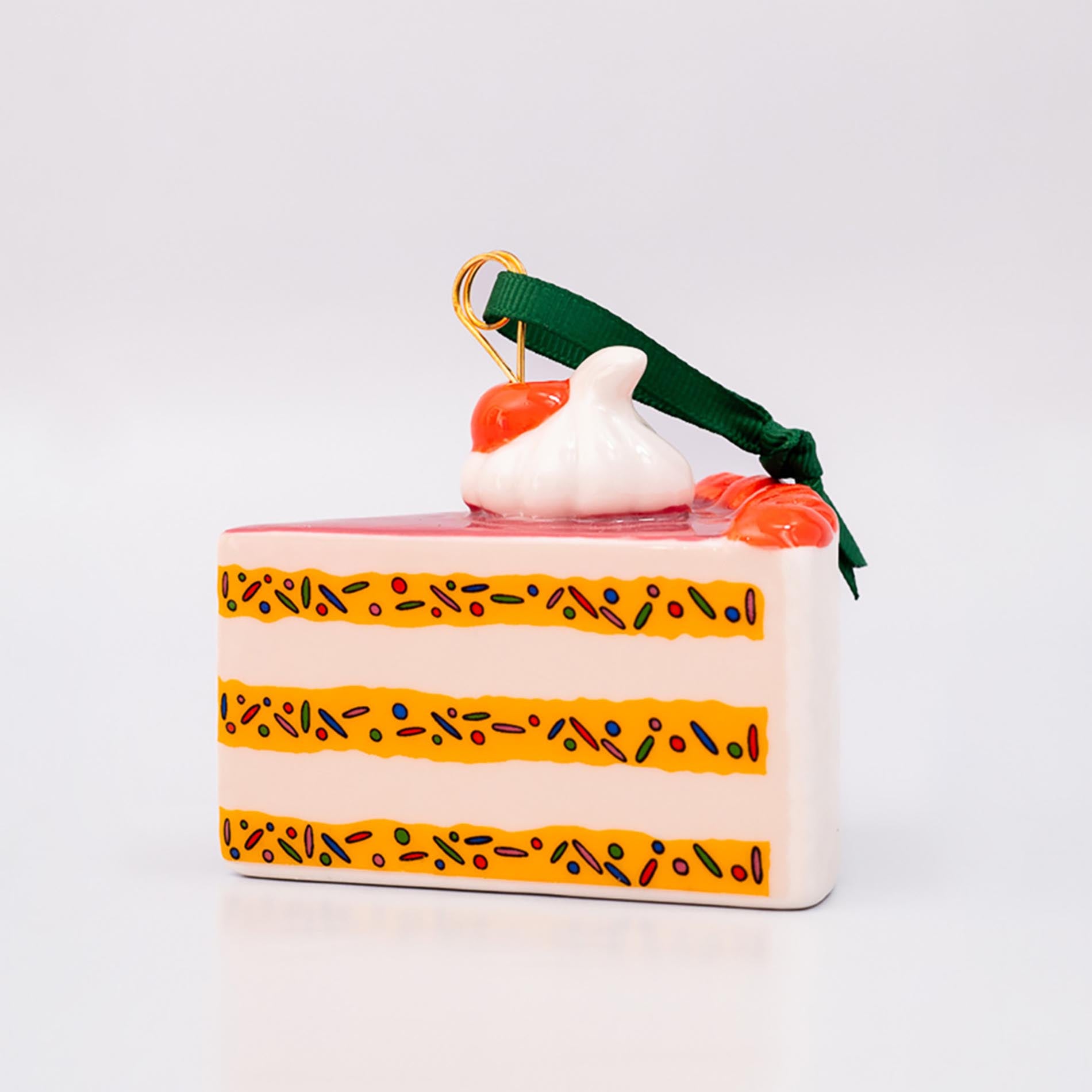 Decorative cake-shaped ornament with a cherry on top against a white background