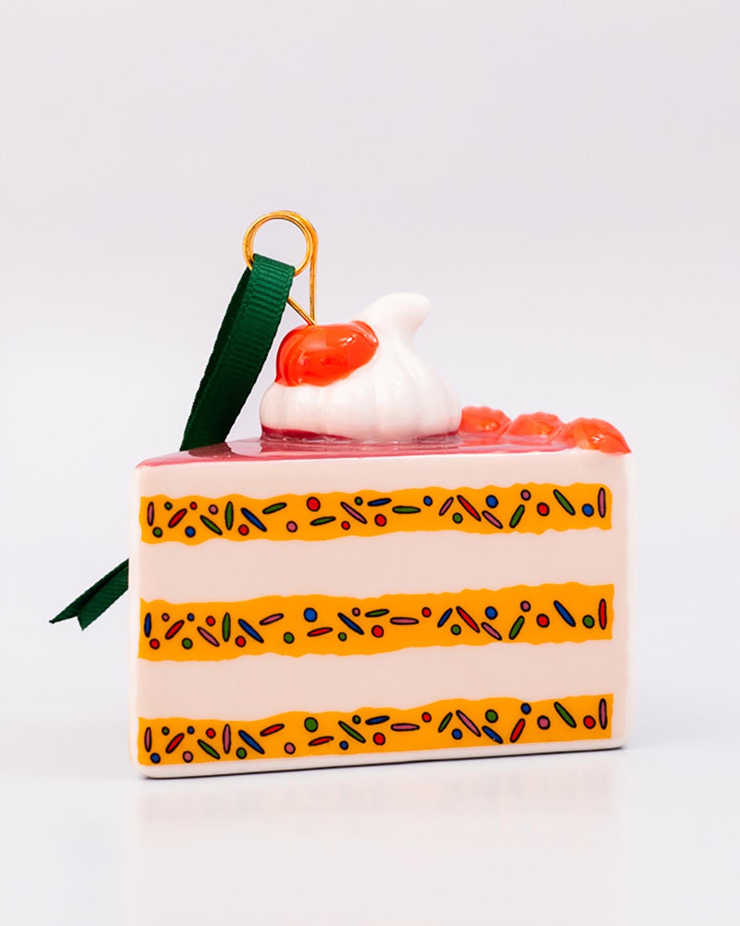 Decorative cake-shaped ornament with a cherry on top against a white background