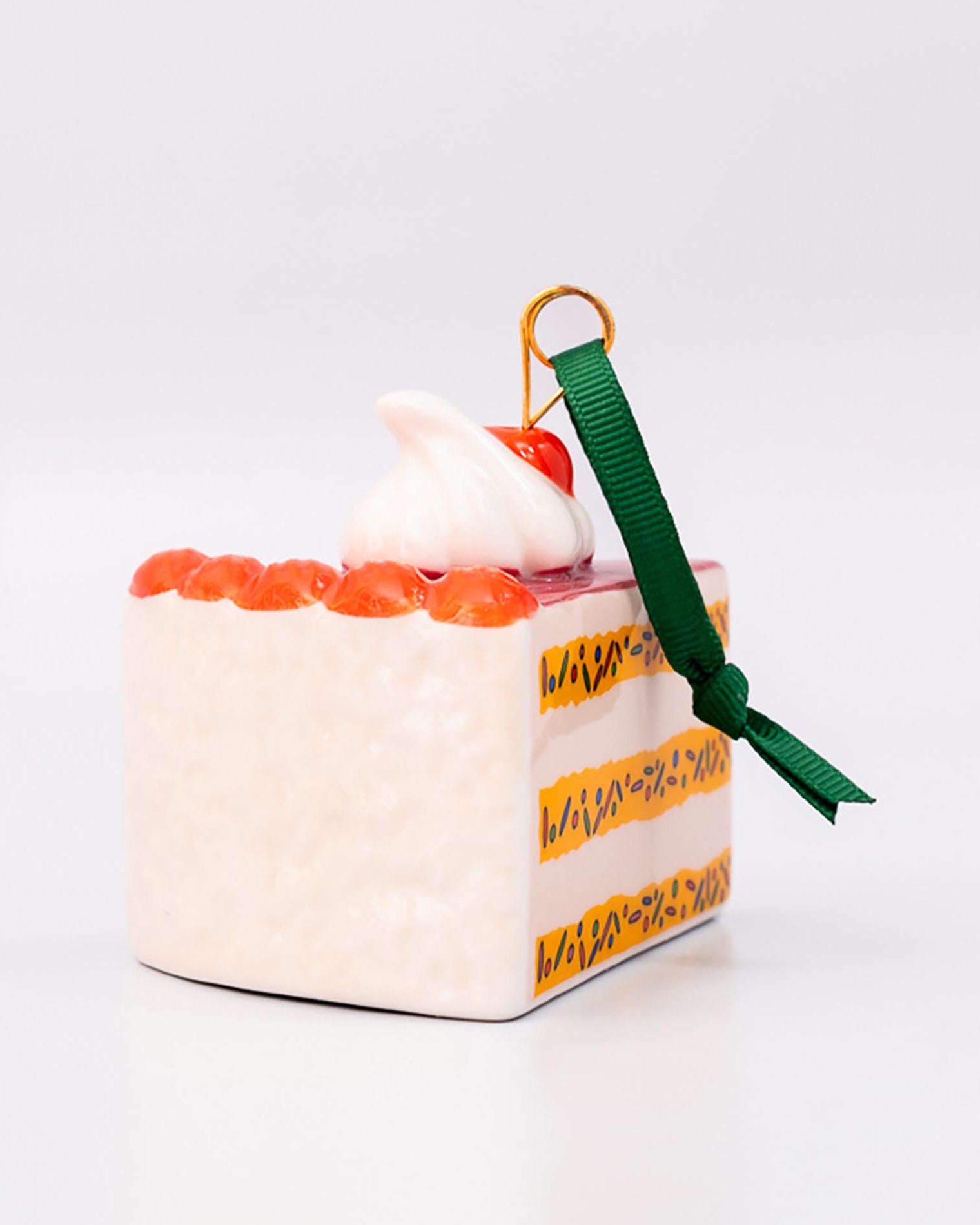 Small cake-shaped ornament with a green ribbon on a white background