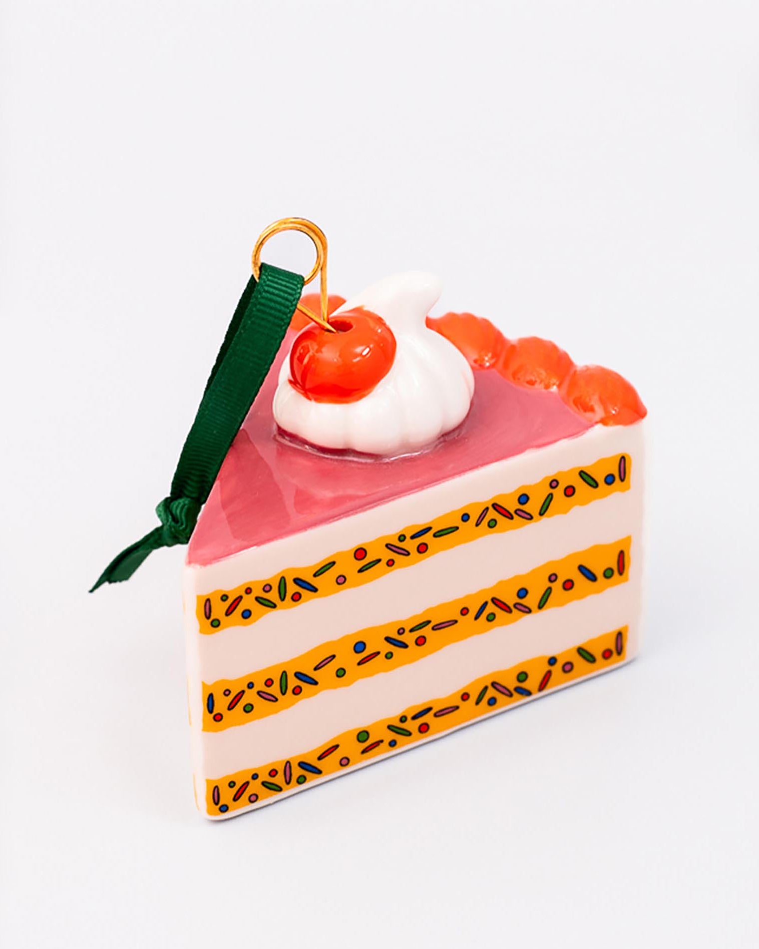 Cake slice ornament with cherry on top against a white background