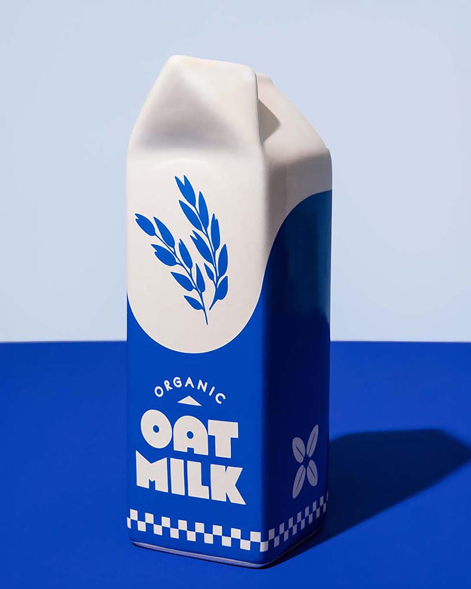 Carton of organic oat milk vase with a blue and white design on a blue background