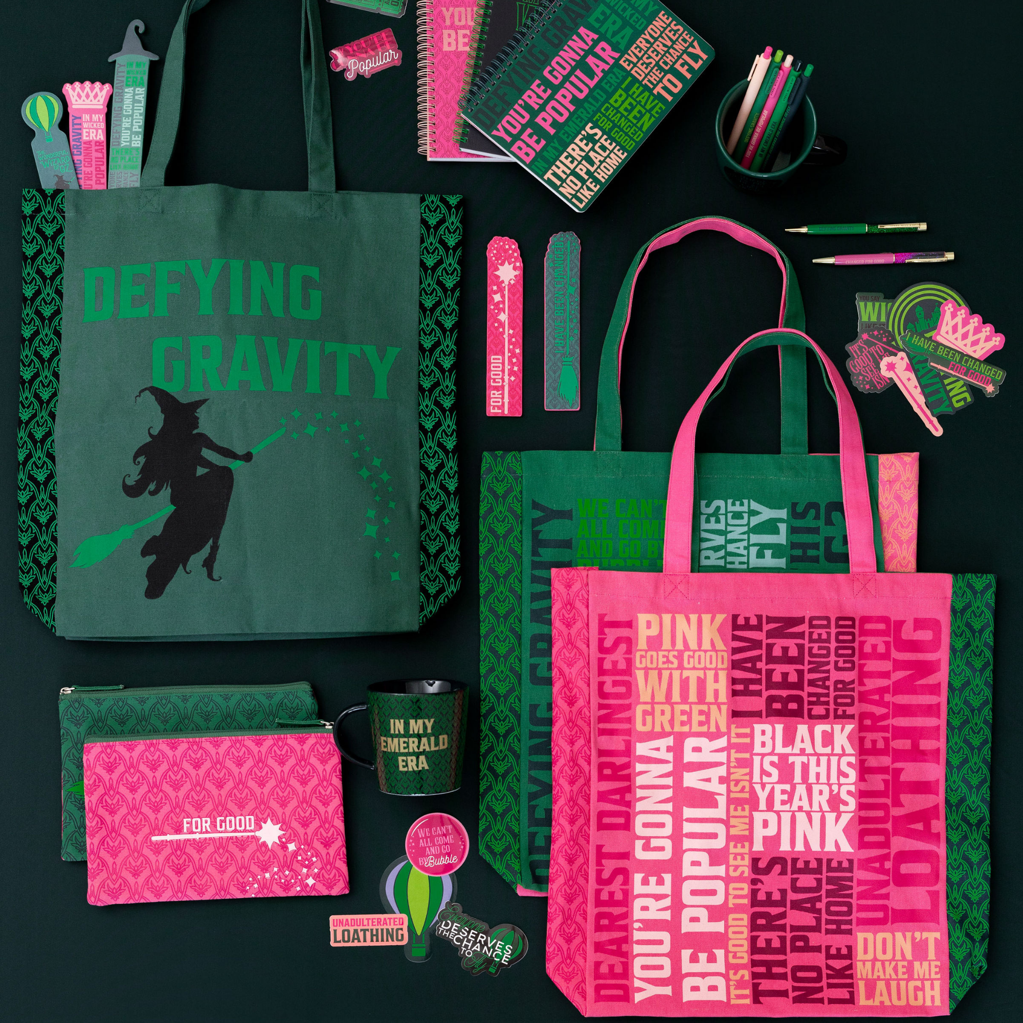 Collection of green and pink tote bags, mugs, and other items with text and graphics on a black background.