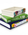 Stack of ceramic book-shaped planters with book title designs on a white background
