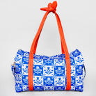 A duffle bag with a blue and white floral tile pattern and bright orange handles tied at the top, shown against a light gray background.
