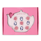 Teapot-shaped tic-tac-toe game with rose and cameo designs on a pink box, brand 'Steel Mill' visible.