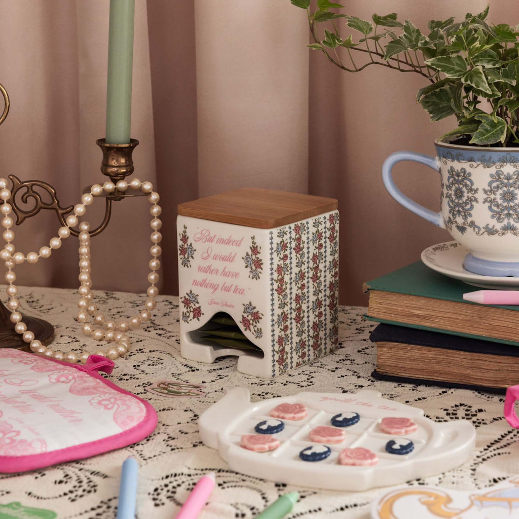 Decorative items on a table including a candle, books, a plant, and a small table with floral design.