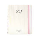 Kate Spade 2027 planner with a cream and gold striped cover, a pink elastic band, and black text on a white background.