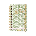 A spiral-bound planner with a green and white palm tree patterned cover, featuring a gold glitter vertical stripe and the cursive brand name 'Lilly Pulitzer' in gold foil on the front.