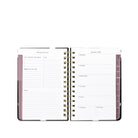 An open spiral-bound planner with white pages, gold-tone coil binding, and muted mauve-pink page headers and tabs on a plain white background.