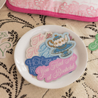 Decorative plate with colorful text and graphics on a lace tablecloth
