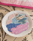 Decorative plate with colorful text and graphics on a lace tablecloth