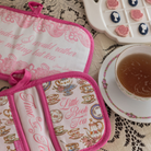 Tea-themed pot holders with decorative text and designs on a lace tablecloth with a cup of tea.