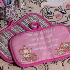 Pink potholder with tea-themed design and quote on a patterned surface