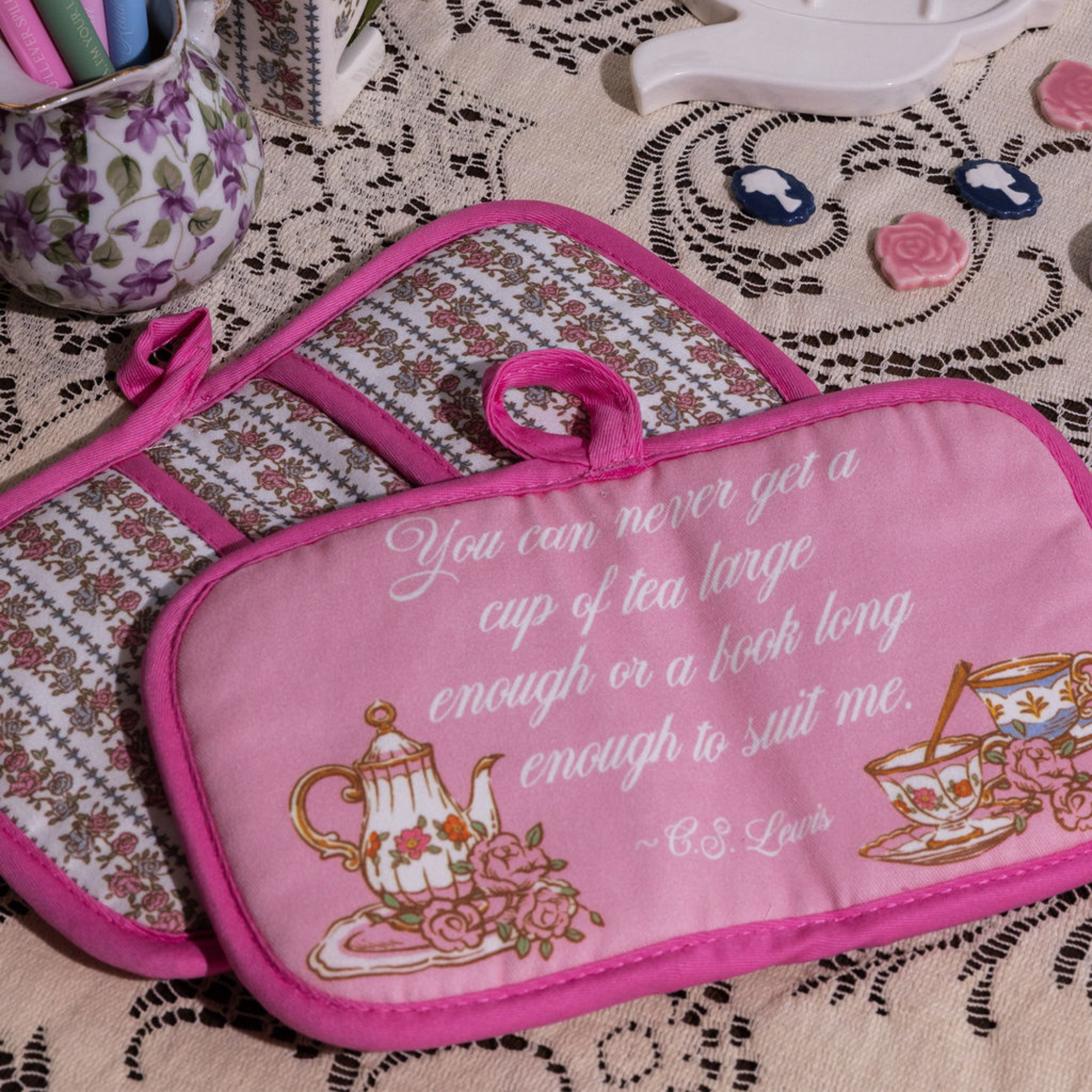 Pink potholder with tea-themed design and quote on a patterned surface