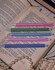 Set of colorful pens on an open book with a pearl necklace.