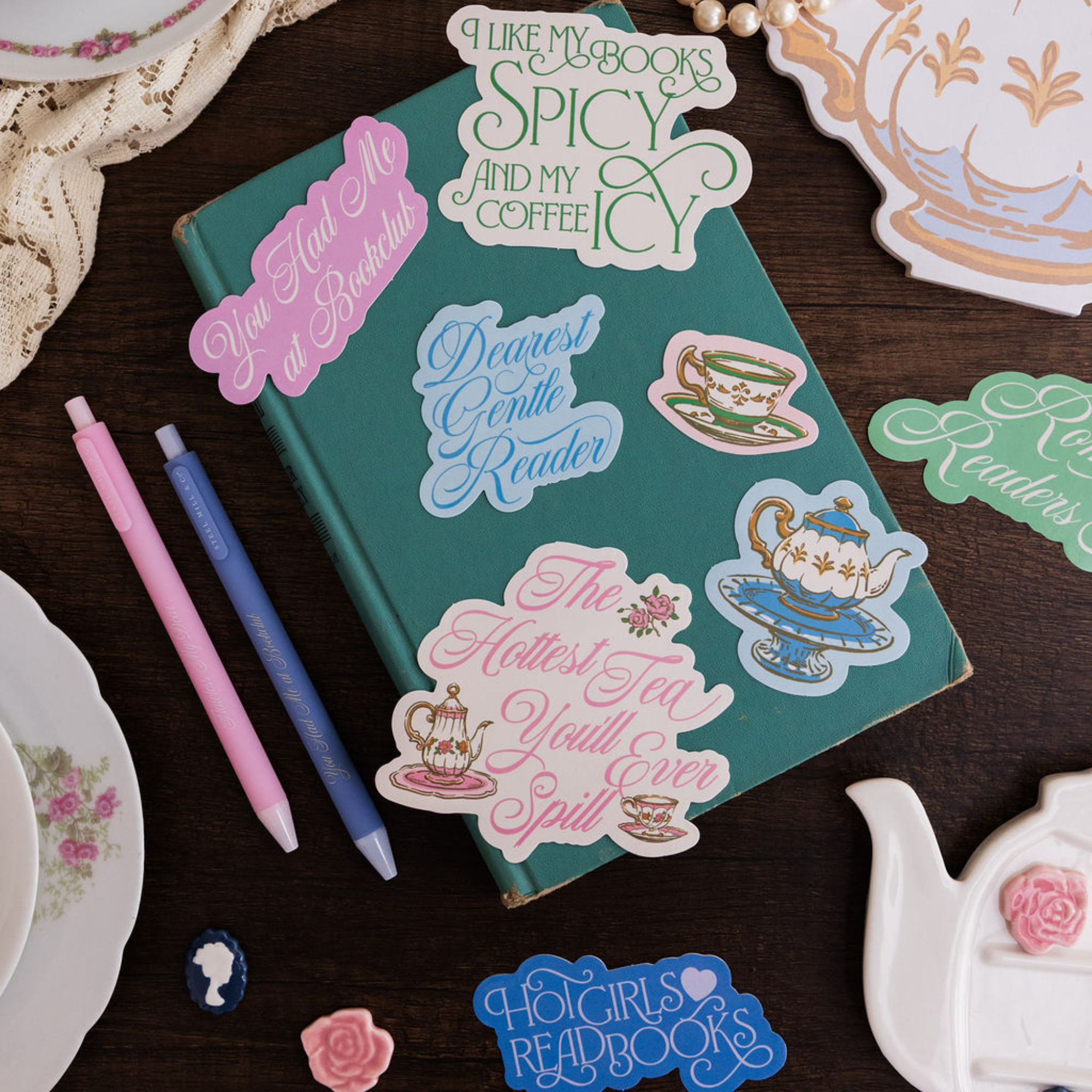 Teal notebook with decorative stickers on a wooden surface with tea-themed items.