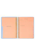 Open spiral-bound planner with peach interior pages on a white background