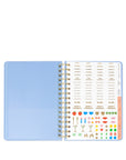 Open planner with light blue cover and colorful stickers on a white background