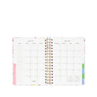 Open planner showing a monthly calendar layout with colorful design elements on a white background.