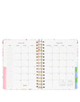 Open planner showing a monthly calendar layout with colorful design elements on a white background.