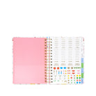 Open planner showing pink cover and colorful interior pages on a white background