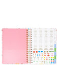 Open planner showing pink cover and colorful interior pages on a white background