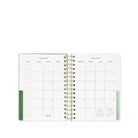 Open planner showing a monthly calendar layout with green binding on a white background