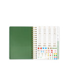 Green notebook with a spiral binding and decorative page on a white background