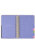 Open planner with purple cover and gold binding on a white background