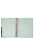 Open planner with a mint green cover and white pages on a white background