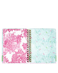 Open planner with pink and white palm tree design on one page and light blue and green patterned design on the other, on a white background.