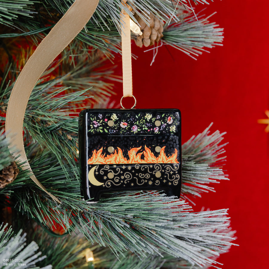black dresser ornament with colorful floral, flames and swirl design hanging on a tree