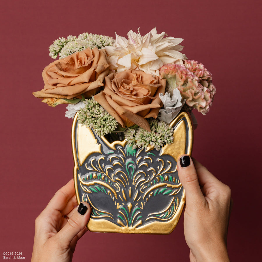 model holding gold spring court mask shaped vase