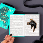 navy and gold accented court wings ornament with gold hanging ribbon in a court of mist and fury book packaging