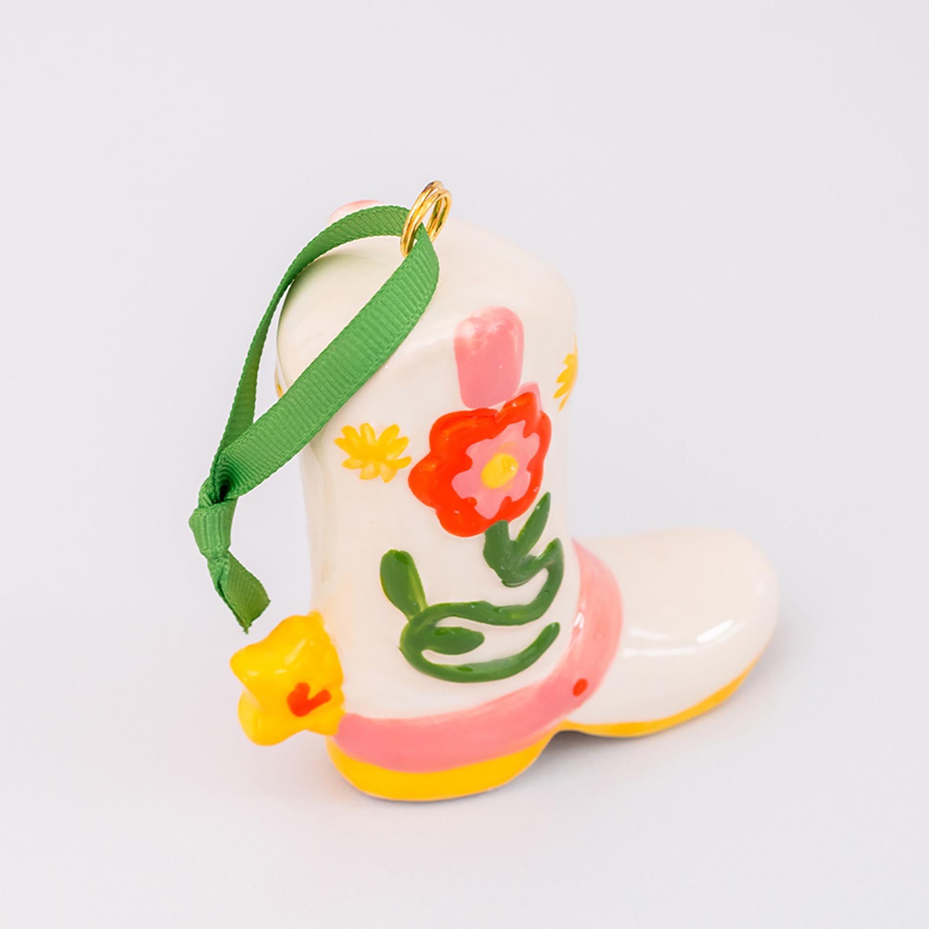 Decorative boot ornament with floral designs and a green ribbon on a light gray background