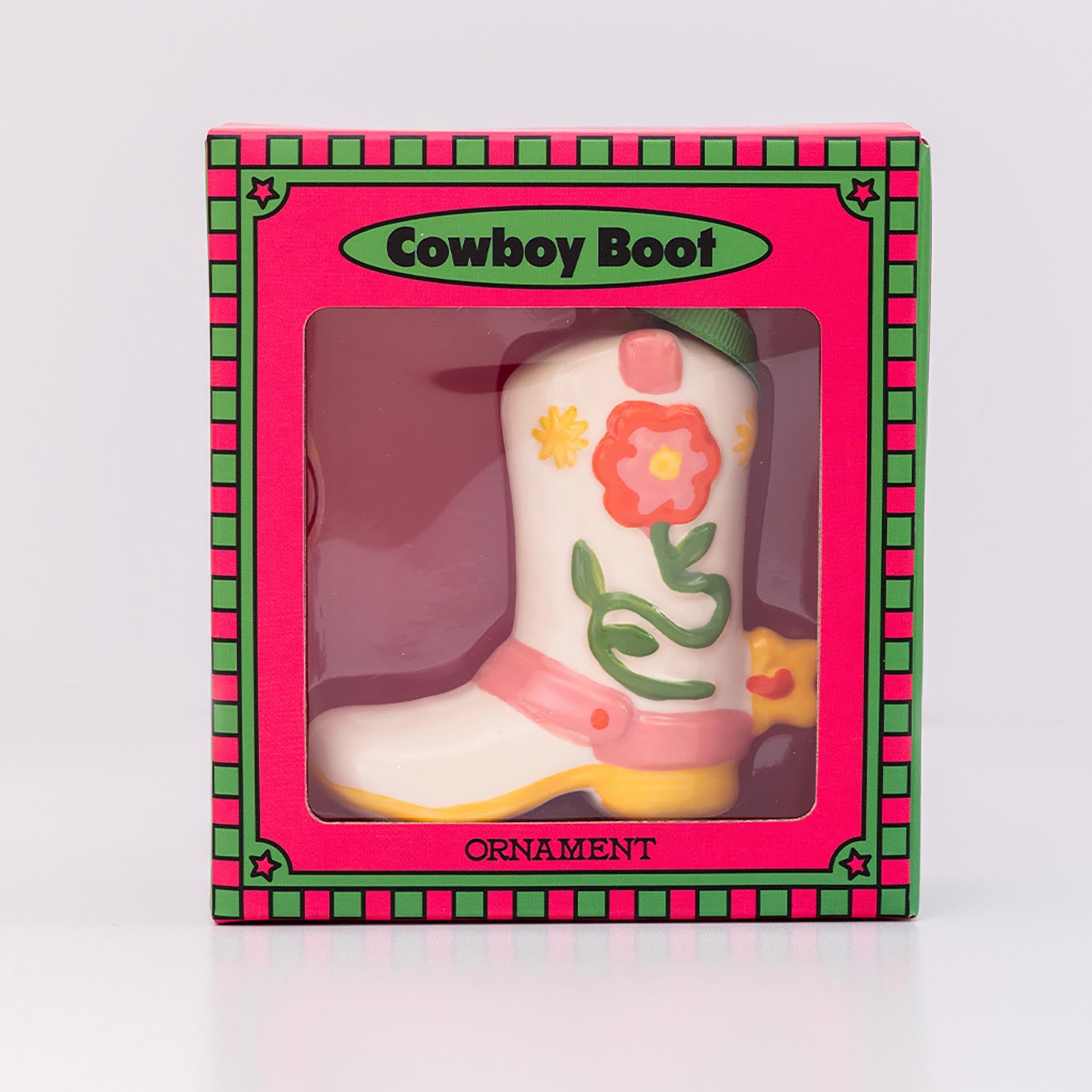 Decorative cowboy boot ornament in a pink box with floral designs on a white background