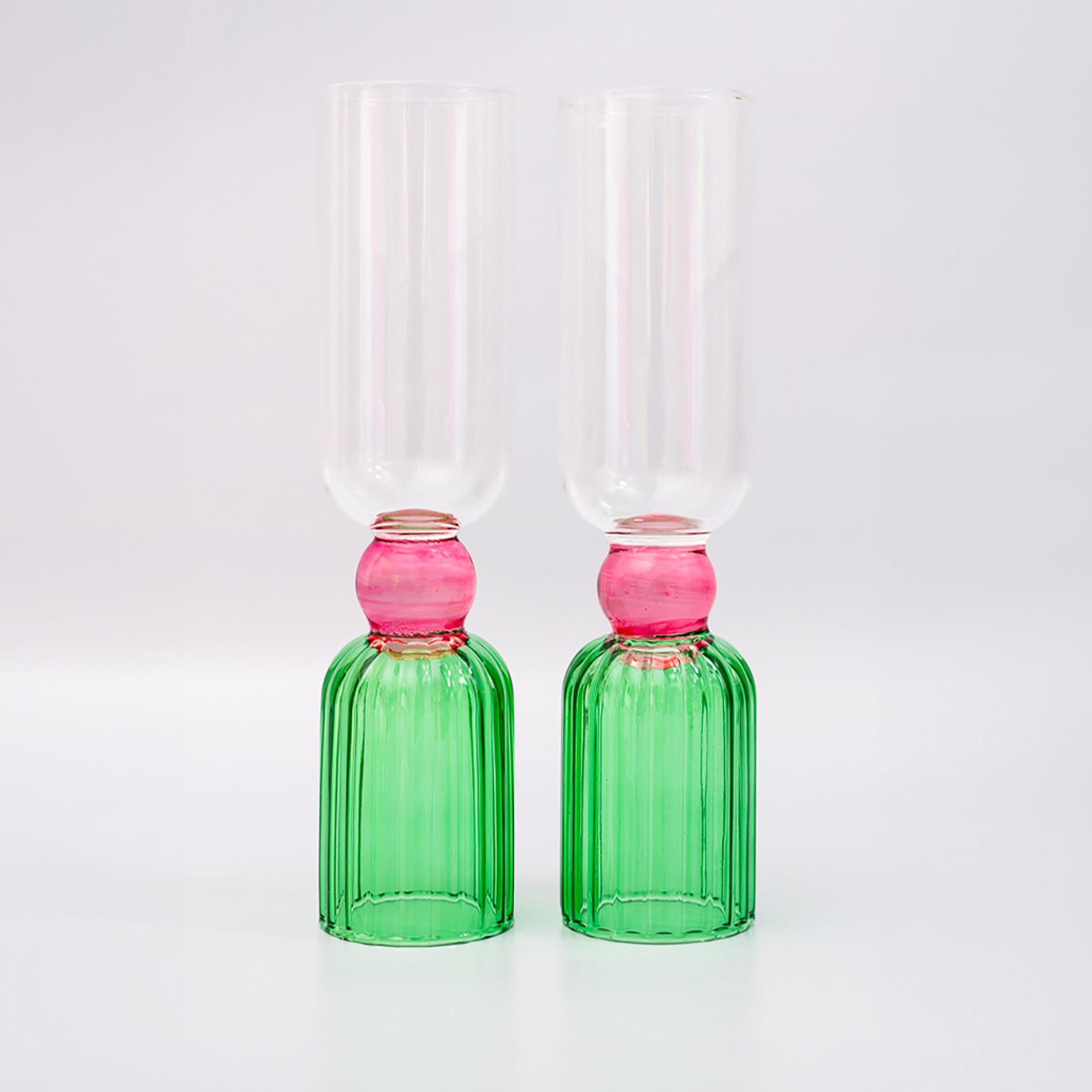 Two green glass bottles with pink stoppers on a white background