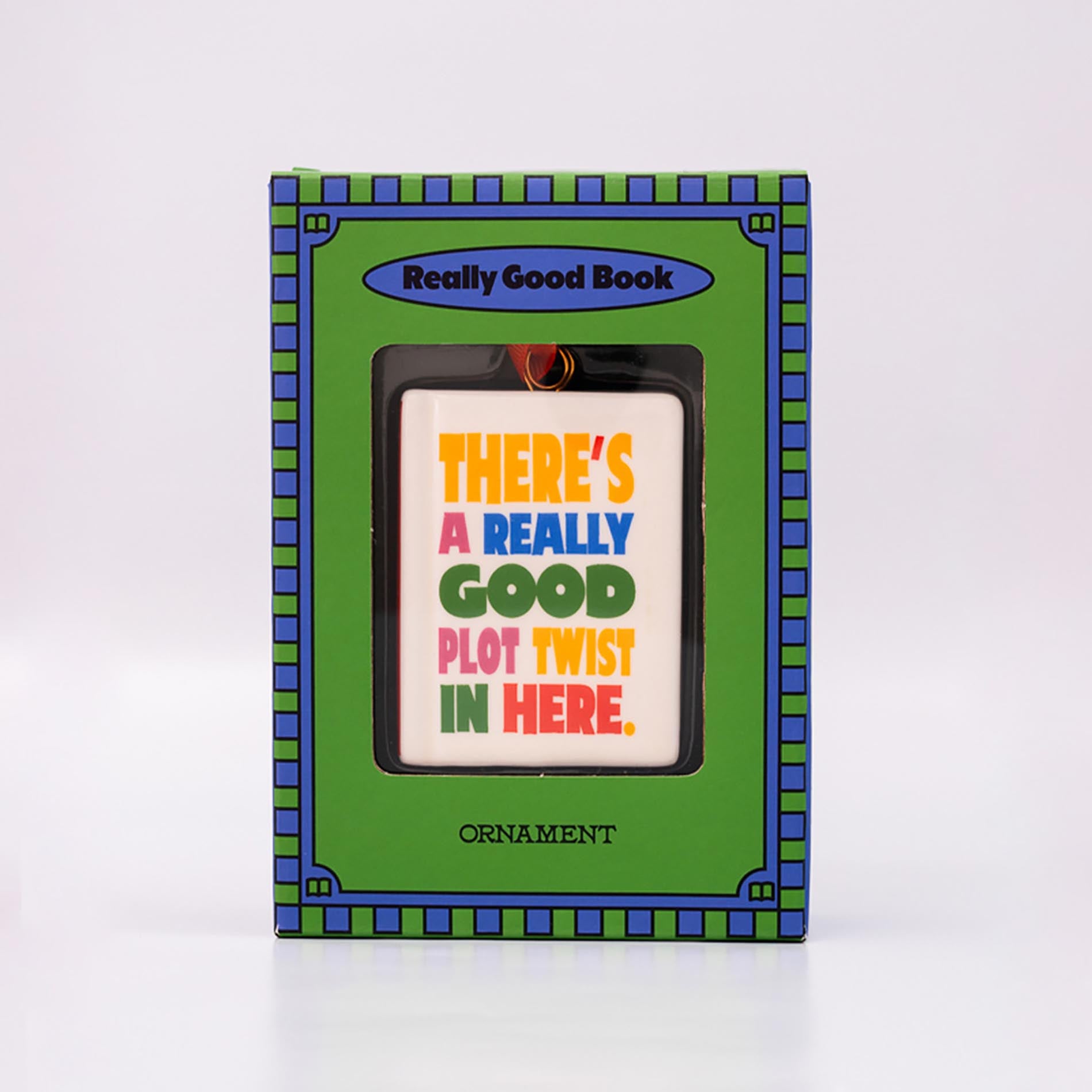 Packaged ornament with 'THERE'S A REALLY GOOD PLOT TWIST IN HERE' and an orange hanger on a white background